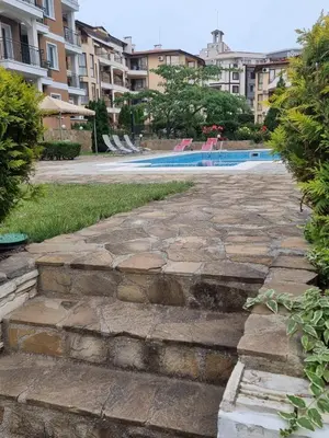 a stone walkway leading to a swimming pool with buildings at Domus Extra Apartment in Sveti Vlas