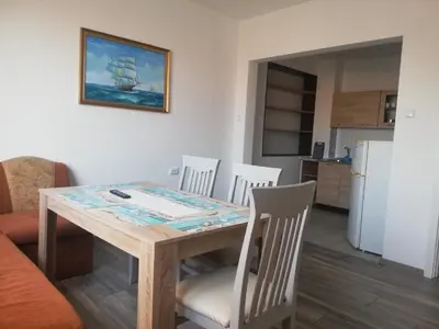 a dining room table with chairs and a kitchen at Апартамент Енигма/Apart Enigma in Sveti Vlas