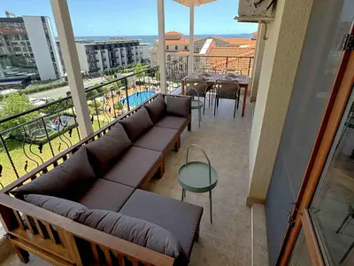 a balcony with couches and a table and a pool at Apartment Royal Bay Sveti Vlas in Sveti Vlas