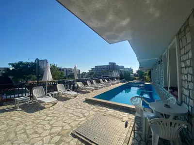 a swimming pool with chairs and tables and a building at FREGATA 2 Studio Sveti Vlas in Sveti Vlas