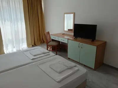 a bedroom with two beds and a desk with a television at Sol e Mar in Sunny Beach