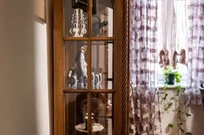 a wooden cabinet with glass shelves with figurines in it at Aristocratic 2bdrm Central Apartment in Varna City