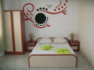 a bedroom with a bed with green sheets and a painting on the wall at Hotel Pasians in Pomorie