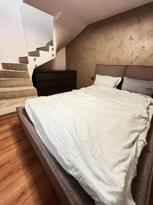 a bedroom with a white bed with a staircase at Amber Home - brand NEW luxury 1 bedroom apartment located in the very city center in Varna City
