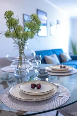 a dining room table with plates and wine glasses at Луксозен Апартамент в Модерна сграда -Молимаркс Делукс Апартамент Бургас in Burgas City