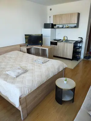 a bedroom with a large bed and a kitchen at Lovely bright studio on Sunny Beach in Sunny Beach