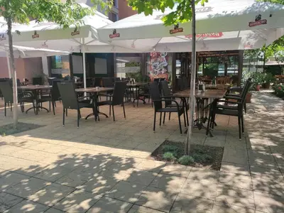 an outdoor patio with tables and chairs and umbrellas at Lovely bright studio on Sunny Beach in Sunny Beach