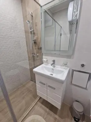 a bathroom with a sink and a shower with a mirror at Дизайнерско Студио в Модерна сграда -Молимаркс Делукс Студио Бургас in Burgas City