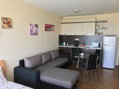 a living room with a couch and a kitchen at Apartments Atia Resort in Chernomorets