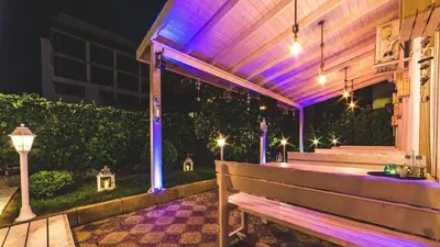 a wooden bench sitting on a patio at night at Beatris Family House in Sunny Beach
