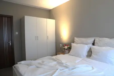 a white bed with white pillows and a cabinet at Апартамент МАРГО in Burgas City