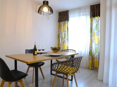 a dining room with a table and chairs with wine glasses at Апартамент МАРГО in Burgas City