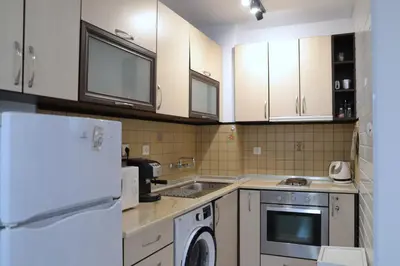 a kitchen with white cabinets and a washer at Апартамент МАРГО in Burgas City