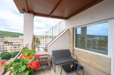 a balcony with a chair and a table and flowers at Sunset Luxury Apartment in Varna City