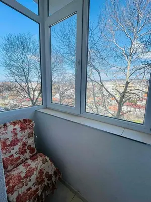 a room with two windows and a chair in front at Просторен апартамент in Varna City