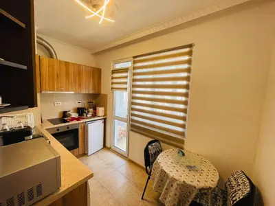 a kitchen with a table and a window with blinds at Просторен апартамент in Varna City