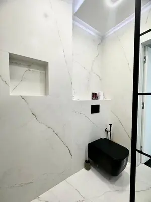 a bathroom with a black toilet and marble walls at Arena MALL Galleria View and Securities Parking2 in Burgas City