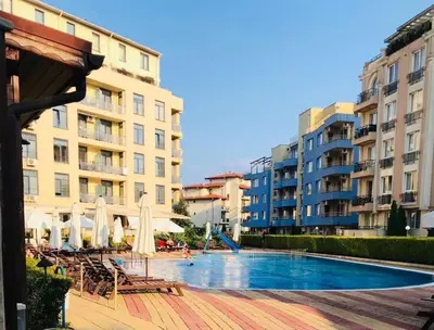 a swimming pool with chairs and umbrellas and buildings at Apartament Esperanza in Sunny Beach