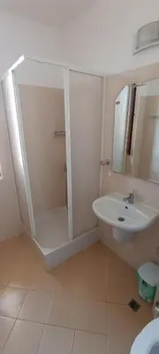 a white bathroom with a shower and a sink at Cozy apartment with sea view and free parking in Pomorie