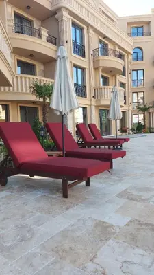 a row of lounge chairs with umbrellas in front of a building at Aphrodite Park in Sunny Beach