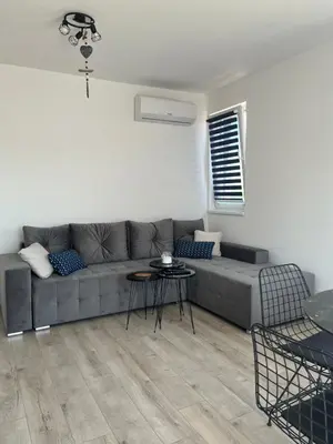 a living room with a gray couch and a table at Zagorovi -1 SP apartments in Burgas City