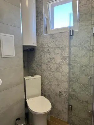 a small bathroom with a toilet and a window at Zagorovi -1 SP apartments in Burgas City