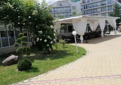 a pavilion with white curtains on a sidewalk with a building at Billy's two- bed apart for Rent at Sunny Beach in Sunny Beach
