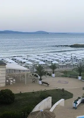 a beach with white umbrellas and the ocean at Studio Festa Pomorie in Pomorie