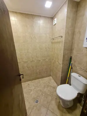 a bathroom with a toilet and a tiled wall at MitProt Panorama Bay 2 Studio 206 in Sveti Vlas