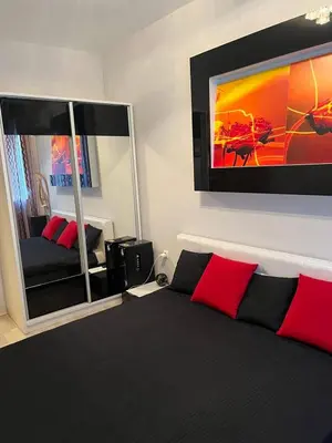 a bedroom with a bed and a tv on the wall at Апартамент Ломбарди in Varna City