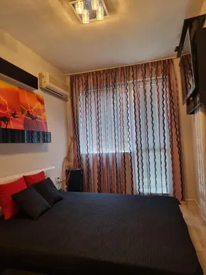 a bedroom with a large bed and a window at Апартамент Ломбарди in Varna City