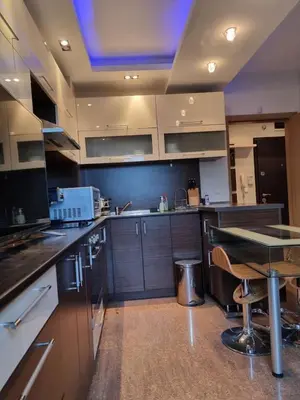 a kitchen with wooden cabinets and a table in it at Апартамент Ломбарди in Varna City