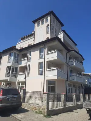 a large white building with a car parked in front of it at Апартаменти Жени in Tsarevo