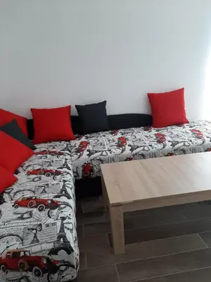 a bedroom with two beds with red pillows and a table at Апартаменти Жени in Tsarevo