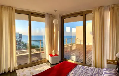 a bedroom with a large window with a view of the ocean at Sea view Penthouse (YooBulgaria) in Obzor