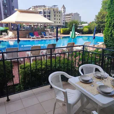 a balcony with a table and chairs and a pool at Sunset Beach 3 - Apartments in Sunny Beach