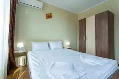 a bedroom with a large white bed with white sheets at Rose Gardens Apart Hotel in Pomorie