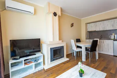 a living room with a table and a fireplace at Rose Gardens Apart Hotel in Pomorie