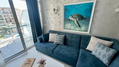 a blue couch in a living room with a turtle painting at Turtle Apartment Sunny Beach in Sunny Beach