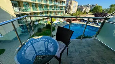a balcony with a table and chairs and a swimming pool at Turtle Apartment Sunny Beach in Sunny Beach