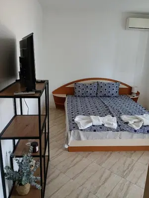 a bedroom with a bed and a flat screen tv at Farlalievi Guest House in Sozopol