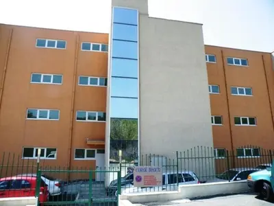 a building with a sign in front of a parking lot at Coral Beach Apartment in Sveti Vlas