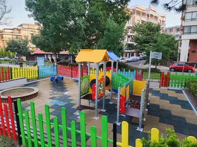 a colorful playground in a park with a fence at VALENCIA GARDENS STUDIO LUX 4 per. in Nesebar