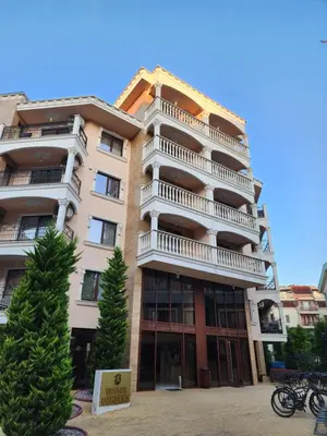 a tall apartment building with a tree in front of it at VALENCIA GARDENS STUDIO LUX 4 per. in Nesebar
