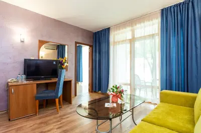 a living room with a tv and a couch and a glass table at Complex Sunrise by HMG - All Inclusive in Sunny Beach