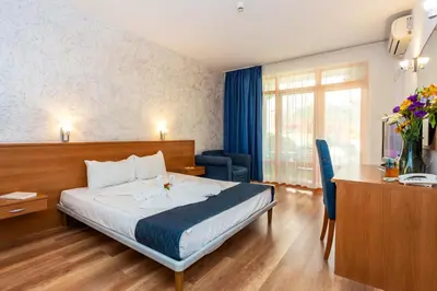 a hotel room with a bed and a desk and a room at Complex Sunrise by HMG - All Inclusive in Sunny Beach