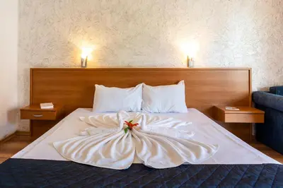 a bed in a hotel room with a flower on it at Complex Sunrise by HMG - All Inclusive in Sunny Beach