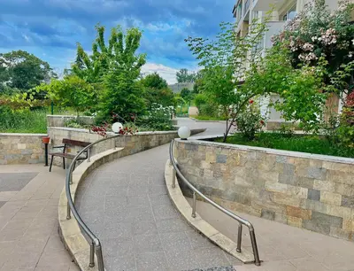 a walkway in a park with a stone wall at SOLITA Apartment with Panoramic View in Byala