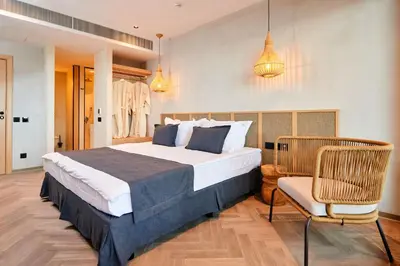 a bedroom with a large bed and a chair at Hotel Fara - Marina Cape in Aheloy