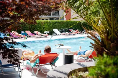 a group of people sitting in chairs by a swimming pool at K&E studios and apartments - All inclusive - Free parking in Sunny Beach